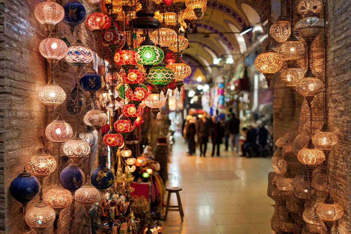 Turkish lantern shop in Grand Bazaar with hanging golden filigree and colorful glass lamps illuminating narrow marketplace co