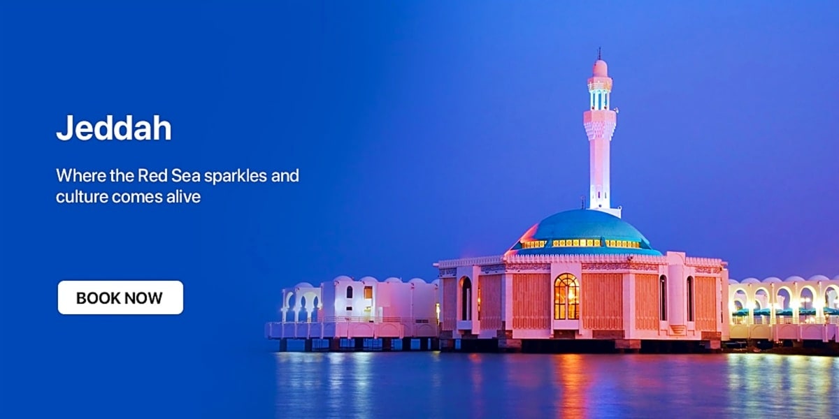 Pink and white mosque with minaret illuminated at dusk on Red Sea waterfront in Jeddah, Saudi Arabia
