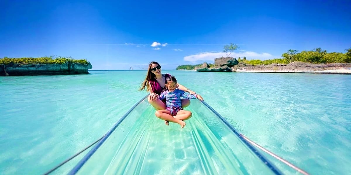 Mother and child sitting in a transparent kayak on turquoise water with limestone cliffs and tropical islands in Boracay