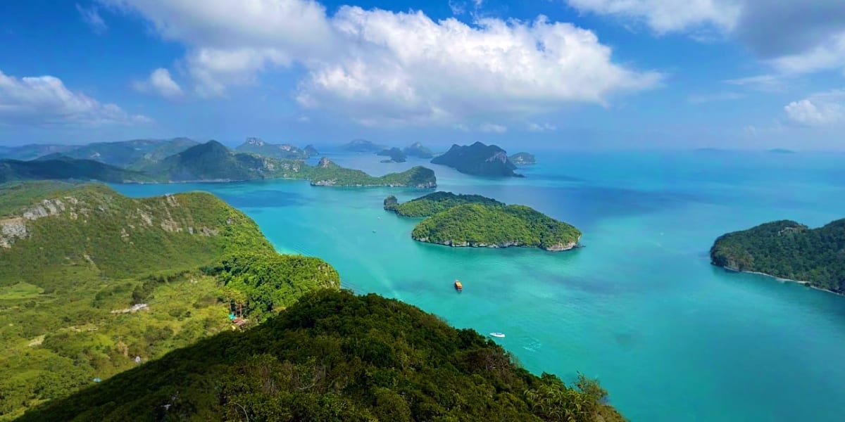 Aerial view of Ang Thong National Marine Park showing turquoise waters, forested limestone islands, and white sand beach in T