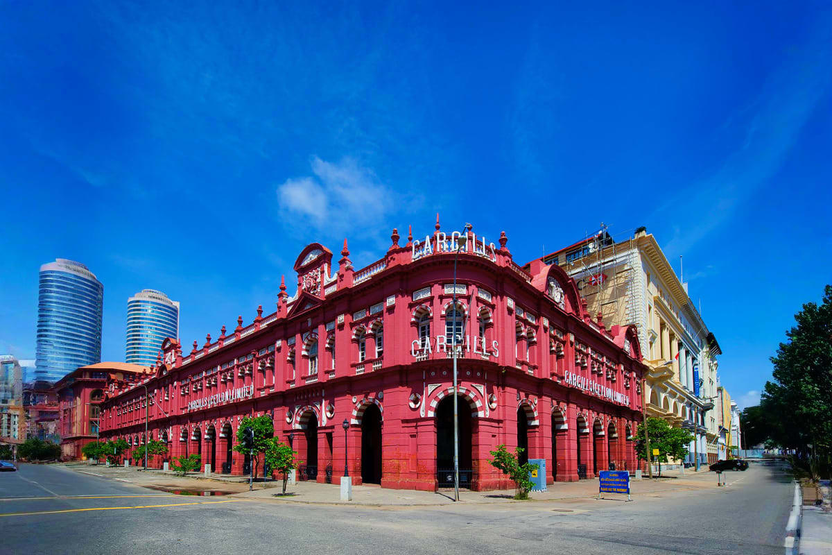 Red colonial-era Cargills building in Colombo with ornate architecture and clock tower against blue sky