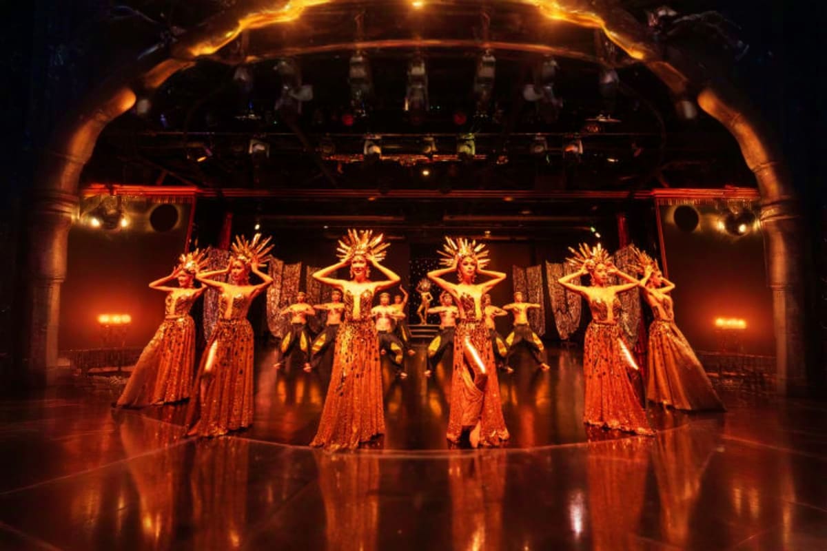 Calypso Bangkok cabaret show with performers in gold sequined costumes and headdresses on illuminated stage