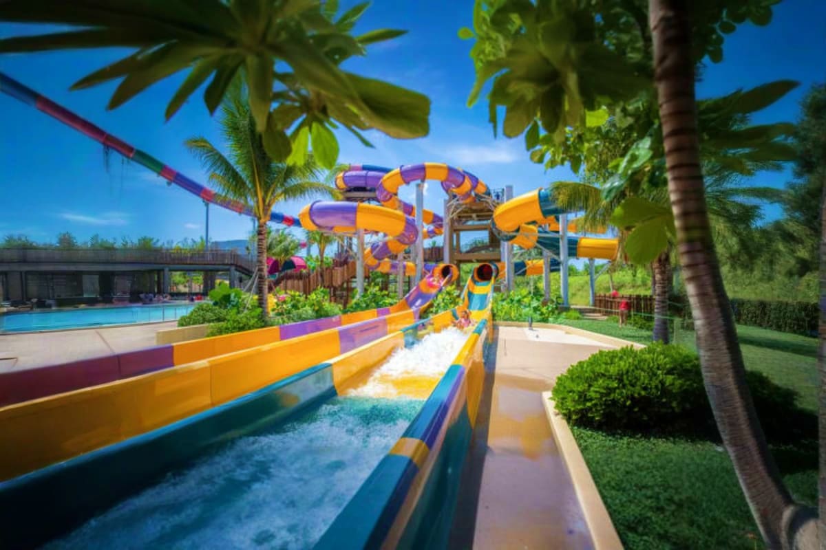 Andamanda Phuket Colorful water slide with twisting orange and purple tubes at Andamanda Phuket water park, surrounded by palm trees and clear