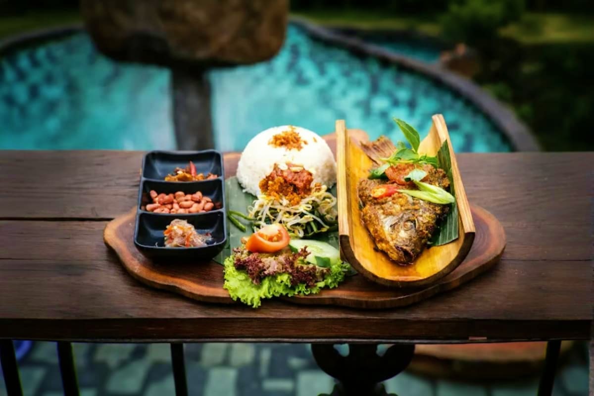 Asian fusion meal plated on wooden board beside swimming pool at D Tukad Coffee Club in Ubud Bali