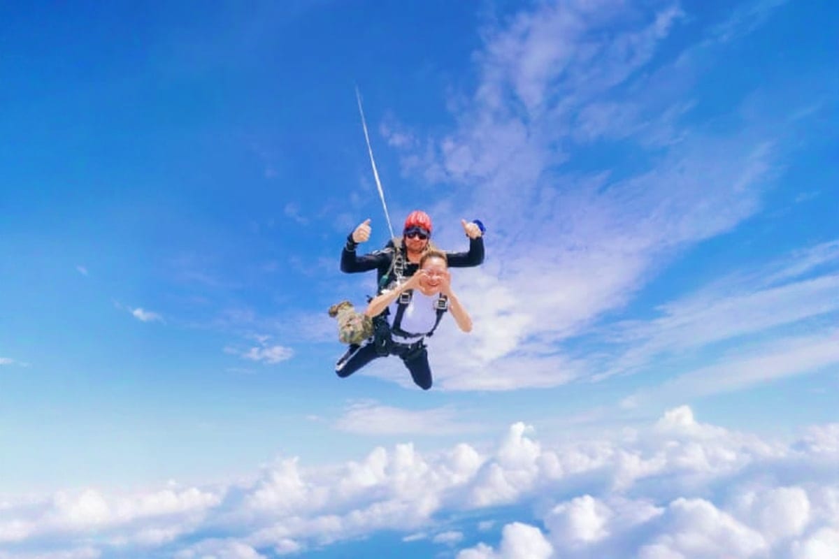 Tandem skydivers in freefall with instructor and passenger above clouds, skydiving activity during Thai Sky Adventures