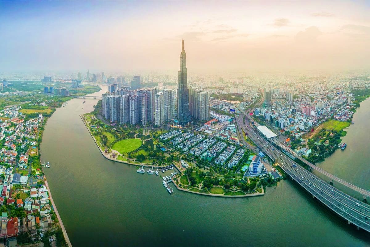 Ho Chi Minh Full day Sharing Tour Aerial view of Ho Chi Minh City skyline with tall skyscraper, river, green parks, bridges, and dense urban development at sun