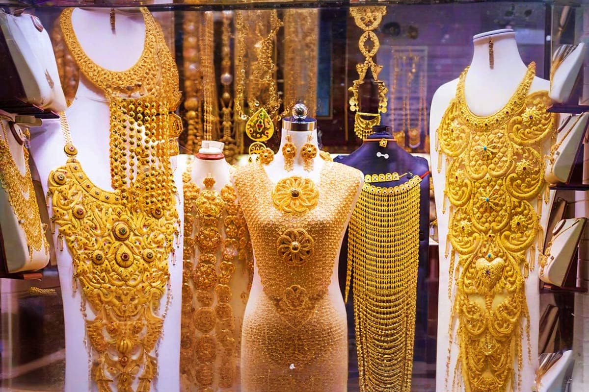 Luxury gold jewelry display in jewelry store window with ornate necklaces and bracelets on white mannequins
