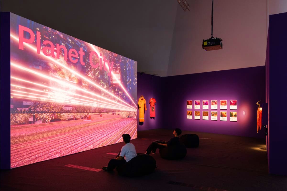ArtScience Museum Singapore Visitors viewing immersive video art installation with "Planet City" display in purple-lit ArtScience Museum gallery space