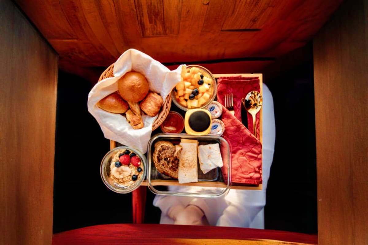 Breakfast in the sky with Balloon flights Overhead view of a luxury breakfast spread on a red table including pastries, fruit, cheese, bread, coffee, and place setting