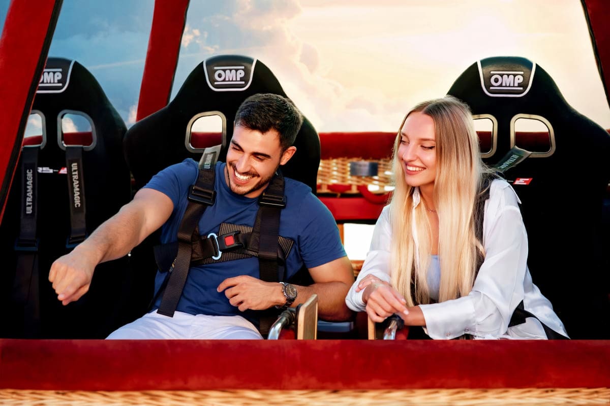 Breakfast in the sky with Balloon flights Couple smiling on red amusement park ride with OMP racing seats against blue sky