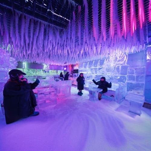Chillout Ice Lounge Dubai Visitors exploring an ice sculpture lounge with purple ambient lighting, ice furniture, and frozen installations in Dubai