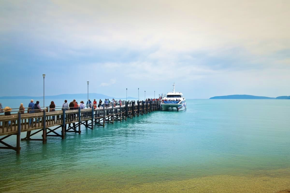 Ferry Tickets for Koh Samui Pier to Koh Tao Maehaad Wooden pier extending into turquoise water with passengers boarding a white and blue ferry boat, islands visible in the dista