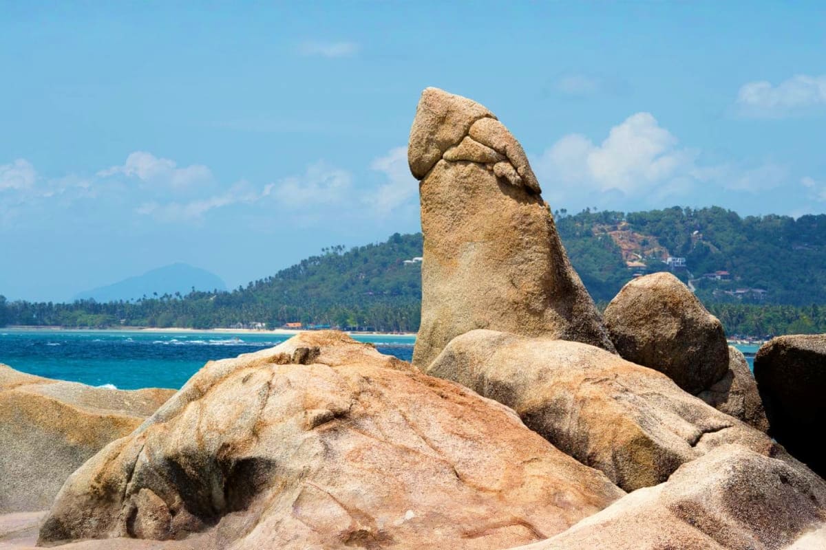 Distinctive granite rock formations on a tropical beach in Koh Samui with turquoise water and forested hillside in background