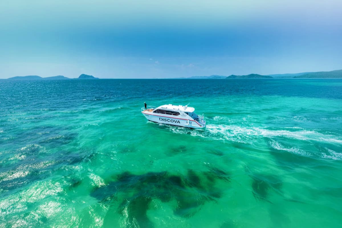 Hong Island Tour by Speed Boat White speedboat named Discova anchored in turquoise tropical waters with distant islands under clear blue sky
