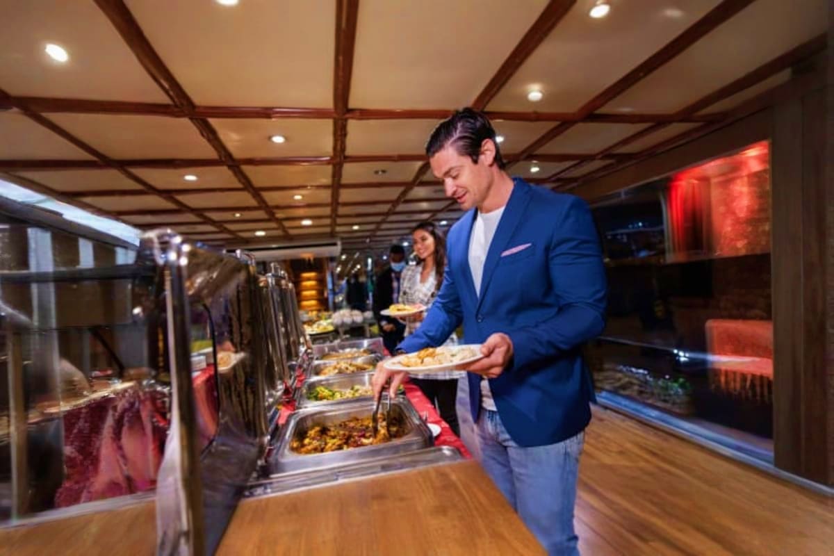Man in blue blazer serving food at buffet counter during luxury dinner cruise on Dubai Canal