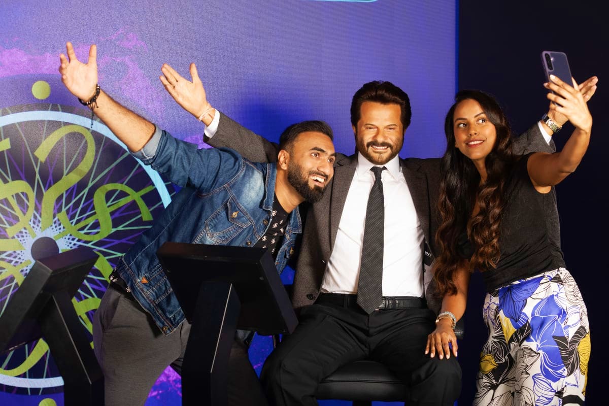 Madame Tussauds Dubai Four people posing together at Madame Tussauds Dubai wax museum, with purple-lit background and decorative elements visible b