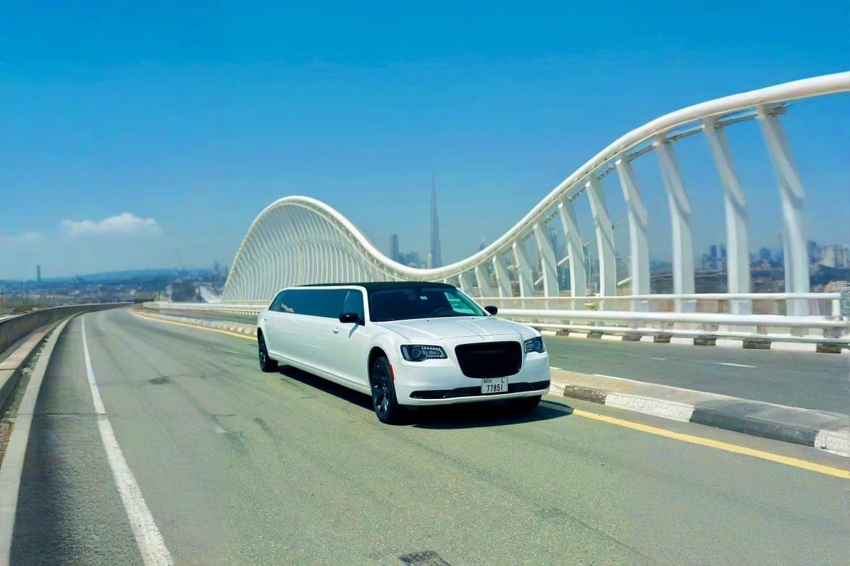 White stretch limousine driving on Sheikh Zayed Bridge with Burj Khalifa visible in Dubai skyline background