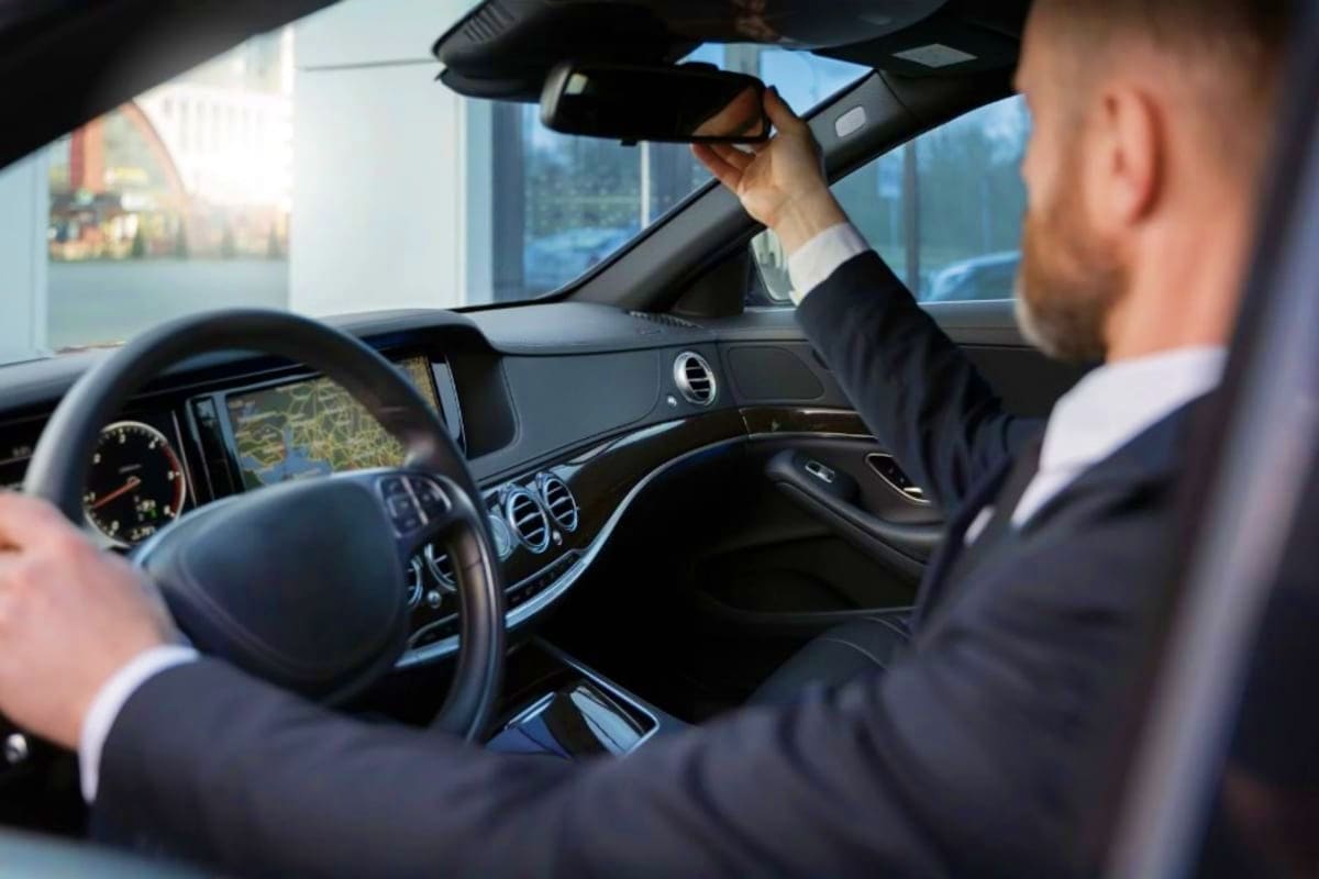 Ramadan Transfers Jeddah Hotel or Airport to Makkah Hotel Businessman in suit adjusting rearview mirror inside luxury car during daytime drive