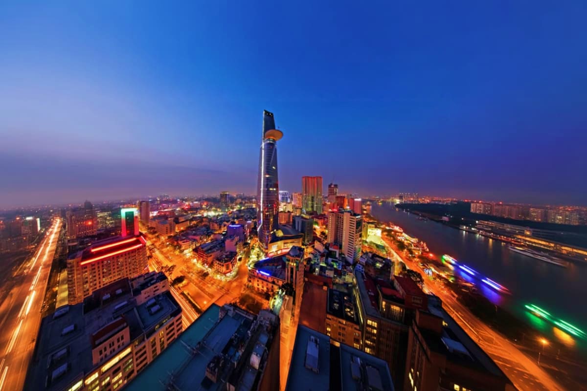 Aerial night view of Ho Chi Minh City skyline from Bitexco Financial Tower with illuminated streets, Saigon River, and surrou