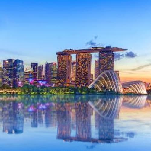 Guided Singapore Layover City Tour Marina Bay Sands and ArtScience Museum reflected in calm water at sunset in Singapore