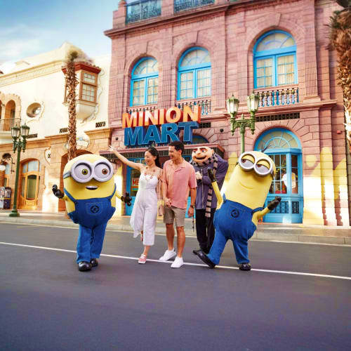Family posing with two Minion characters in front of Minion Market attraction at Universal Studios Singapore