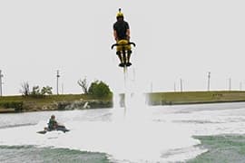 Jetovator Tour Dubai Person riding Jetovator water jet pack flying above Dubai water with another person in jet ski below