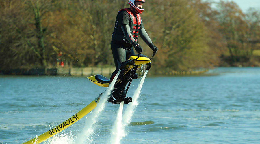 Jetovator Tour Dubai Person riding a yellow and black jetovator above water with trees in background, performing water propulsion sport activity