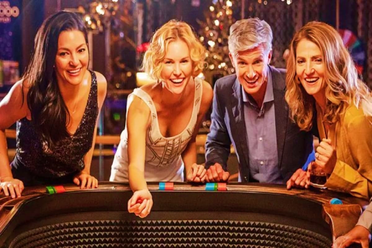 Four adults enjoying roulette at a casino table with holiday decorations and twinkling lights in background