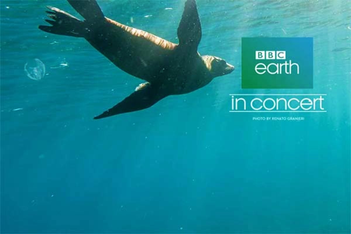 Seal swimming underwater in turquoise ocean water with BBC Earth In Concert logo