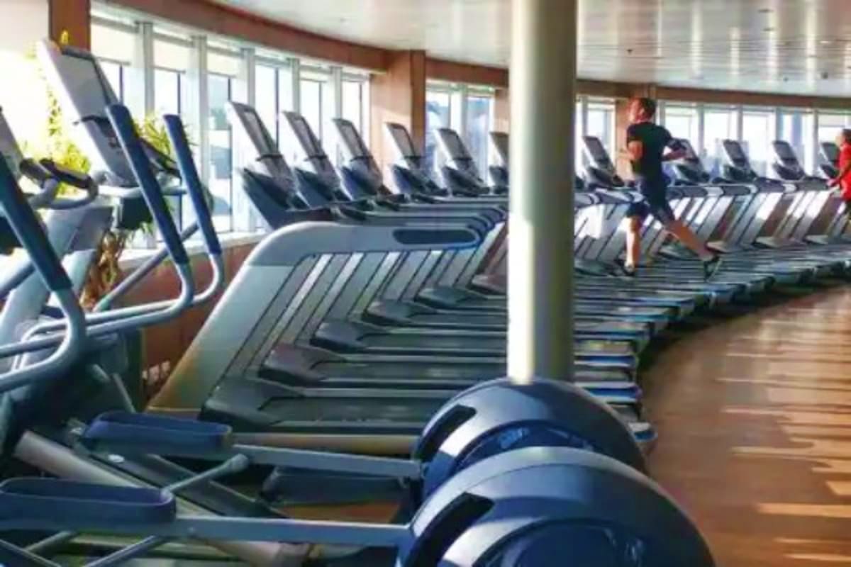 Modern gym with rows of treadmills and exercise equipment overlooking ocean windows on Nieuw Statendam cruise ship