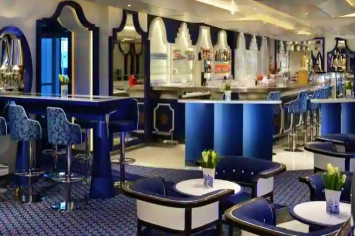 Modern cruise ship bar and lounge with blue and black decor, bar seating, and contemporary furniture
