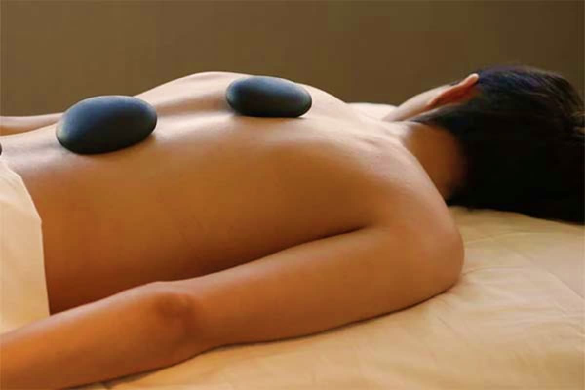 Woman receiving hot stone massage therapy on back during spa treatment