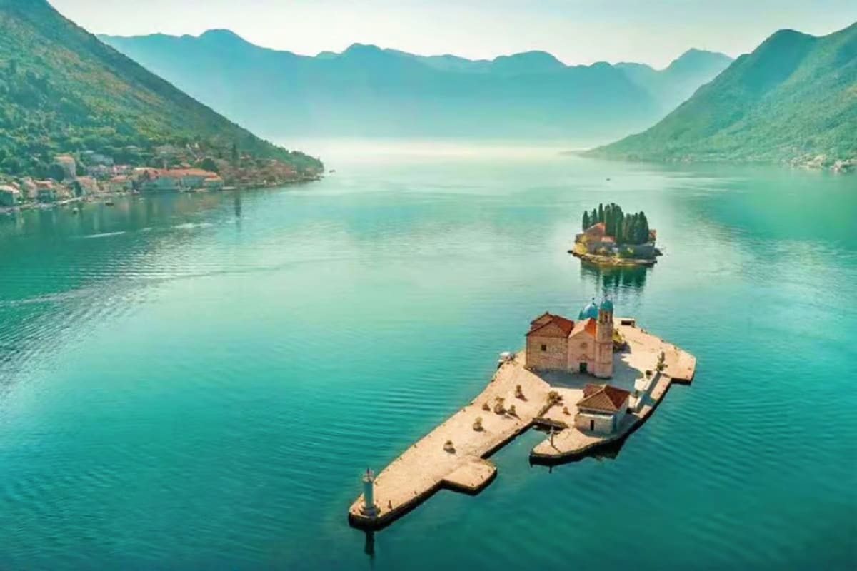 Two small islands with historic stone churches in turquoise bay surrounded by green mountains in Bay of Kotor, Montenegro