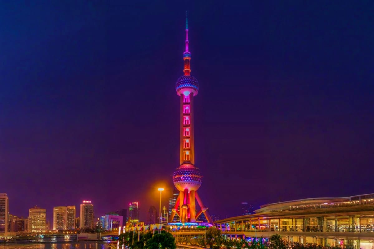 Oriental Pearl Tower illuminated in pink and purple lights at night in Shanghai, China cityscape