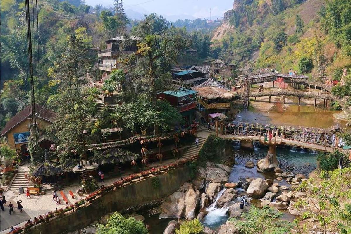 Mountain village with traditional wooden structures nestled in lush valley beside flowing river and stone bridges, Vietnam hi