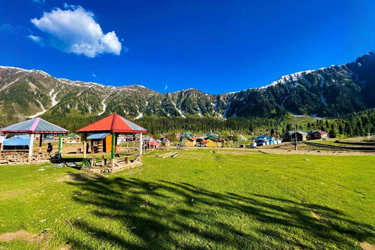 Alpine meadow with colorful market stalls and snow-capped mountains, Kel Suu lake valley, Kyrgyzstan