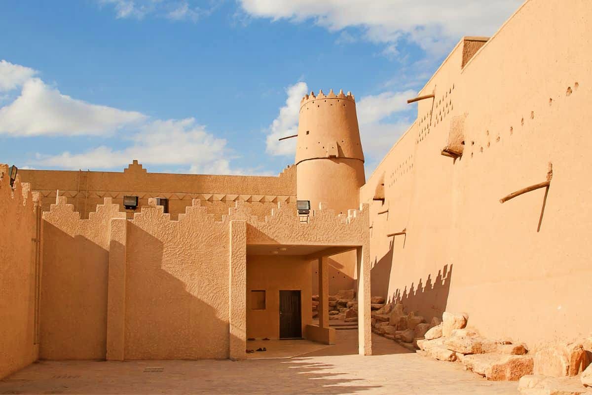 Historic clay fort with crenellated walls and central tower under blue sky, Masmak Fort in Riyadh, Saudi Arabia