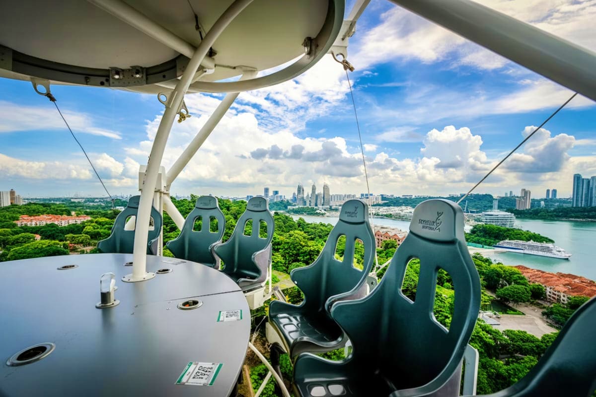 Singapore and Malaysia-Duo View from Sentosa Skyline Luge ride showing empty seats overlooking Singapore skyline, green forests, and cruise ship in harb