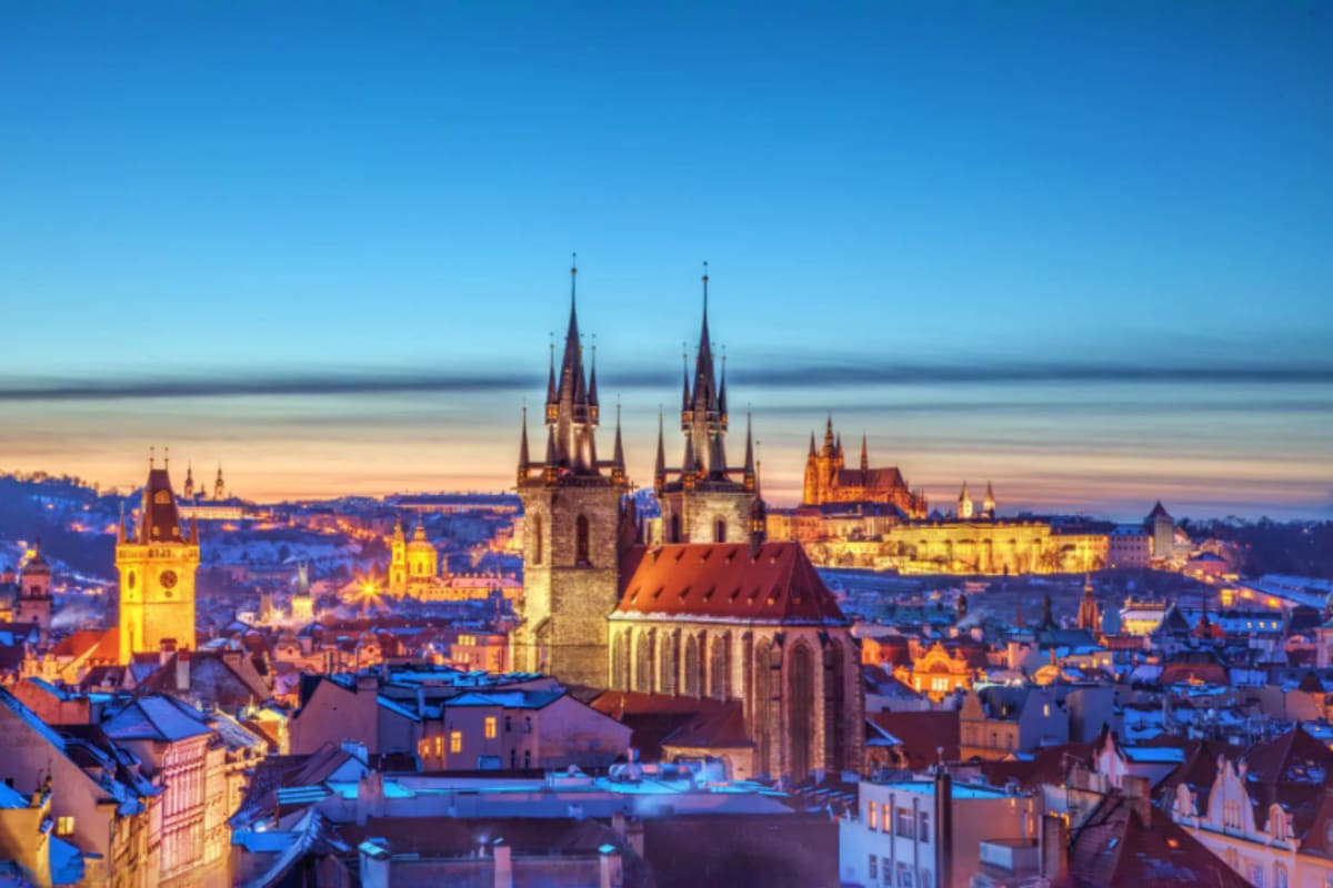Central Europe Romance Tour With Prague to Venice for Couples Prague cityscape at twilight showing Church of Our Lady before Tyn with twin spires and historic architecture illuminated at