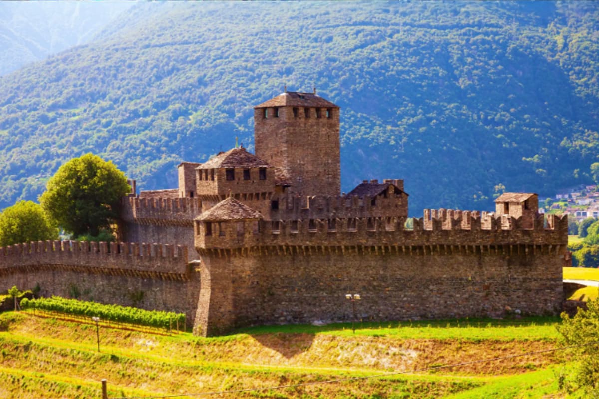 Central Europe Romance Tour With Prague to Venice for Couples Medieval stone castle with crenellated walls and tower surrounded by green valley and forested mountains in Central Europe