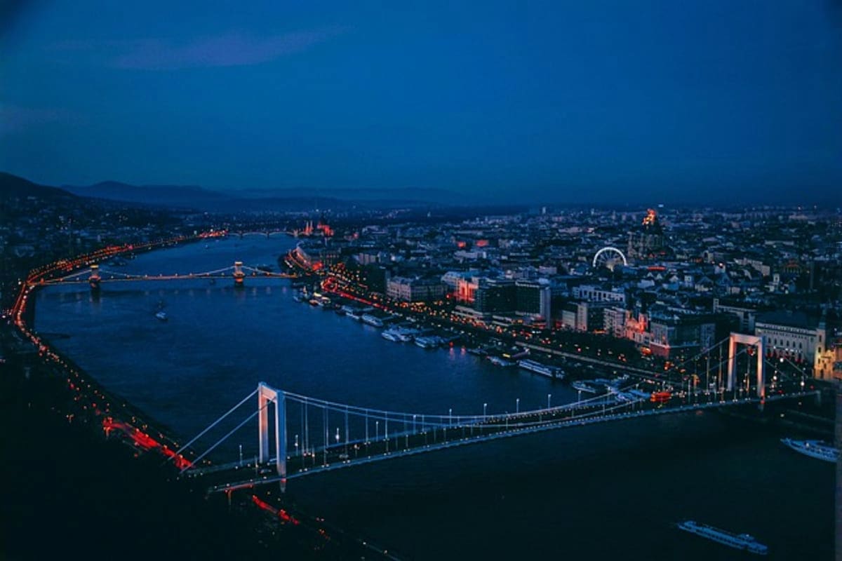 Aerial view of Budapest cityscape at dusk with illuminated bridges spanning the Danube River and lit buildings reflected in b