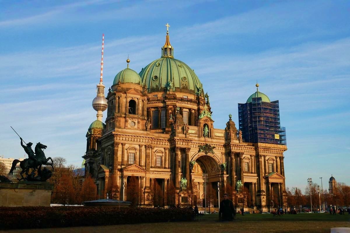 Berlin Cathedral with its distinctive copper dome and neoclassical architecture, featuring the TV Tower and modern cityscape 