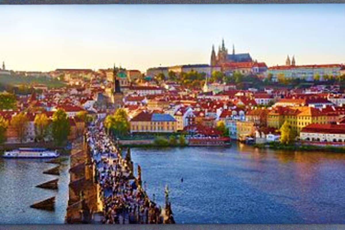Prague cityscape with colorful historic buildings, Vltava River, Charles Bridge, and St. Vitus Cathedral in background