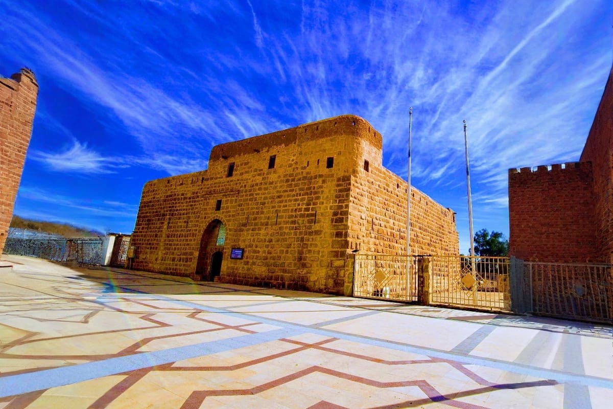 Ancient sandstone fortress with decorative courtyard floor under blue sky in Tabuk desert region