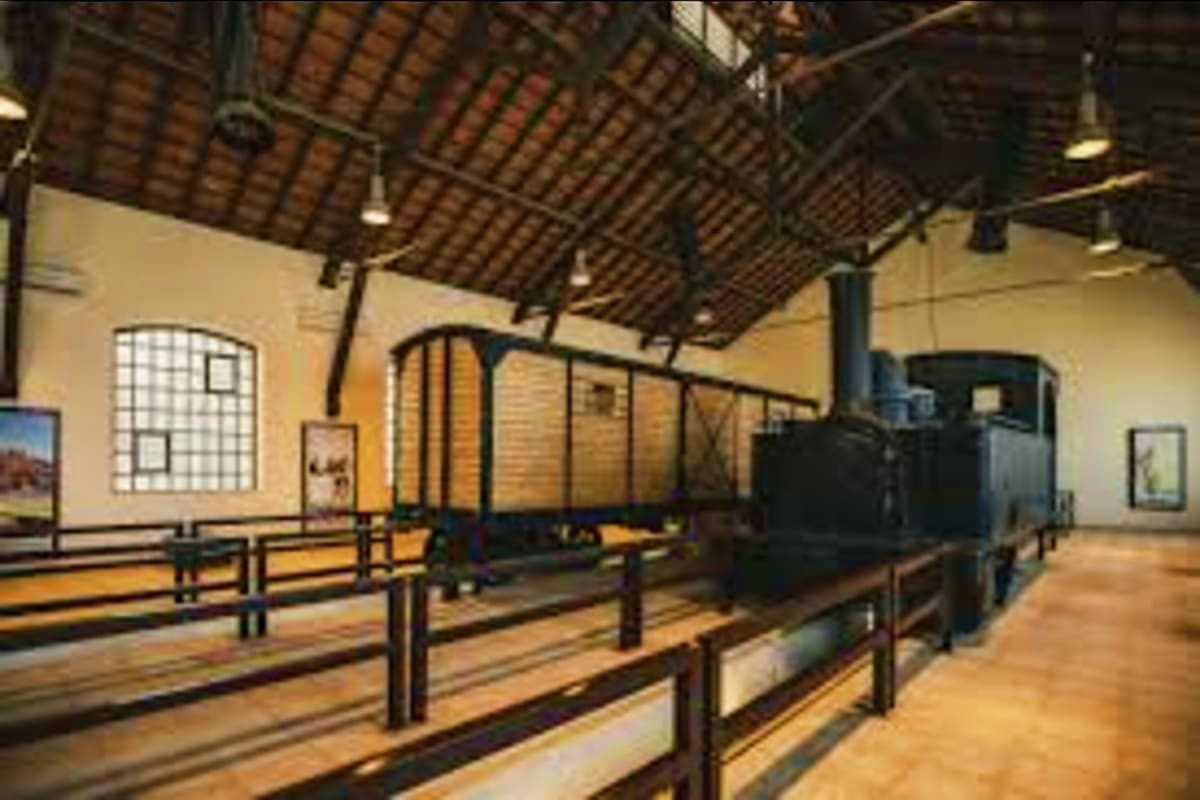 Historic railway station interior with vintage steam locomotive and passenger cars on tracks