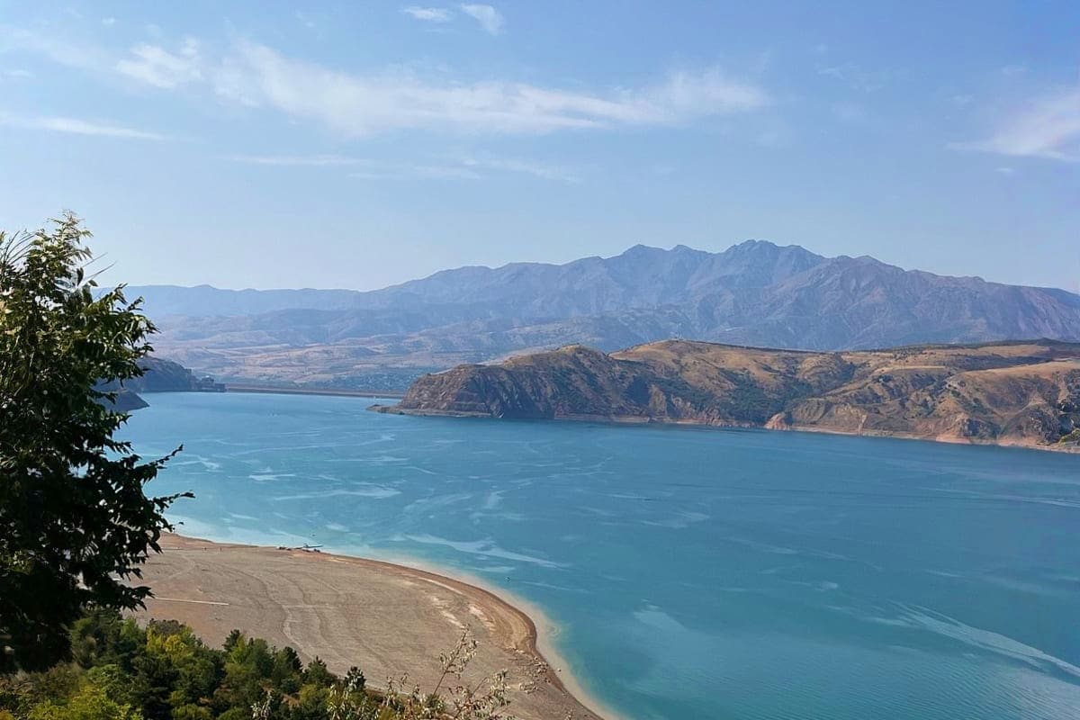 Turquoise Lake Issyk-Kul surrounded by snow-capped mountains and arid landscape in Uzbekistan