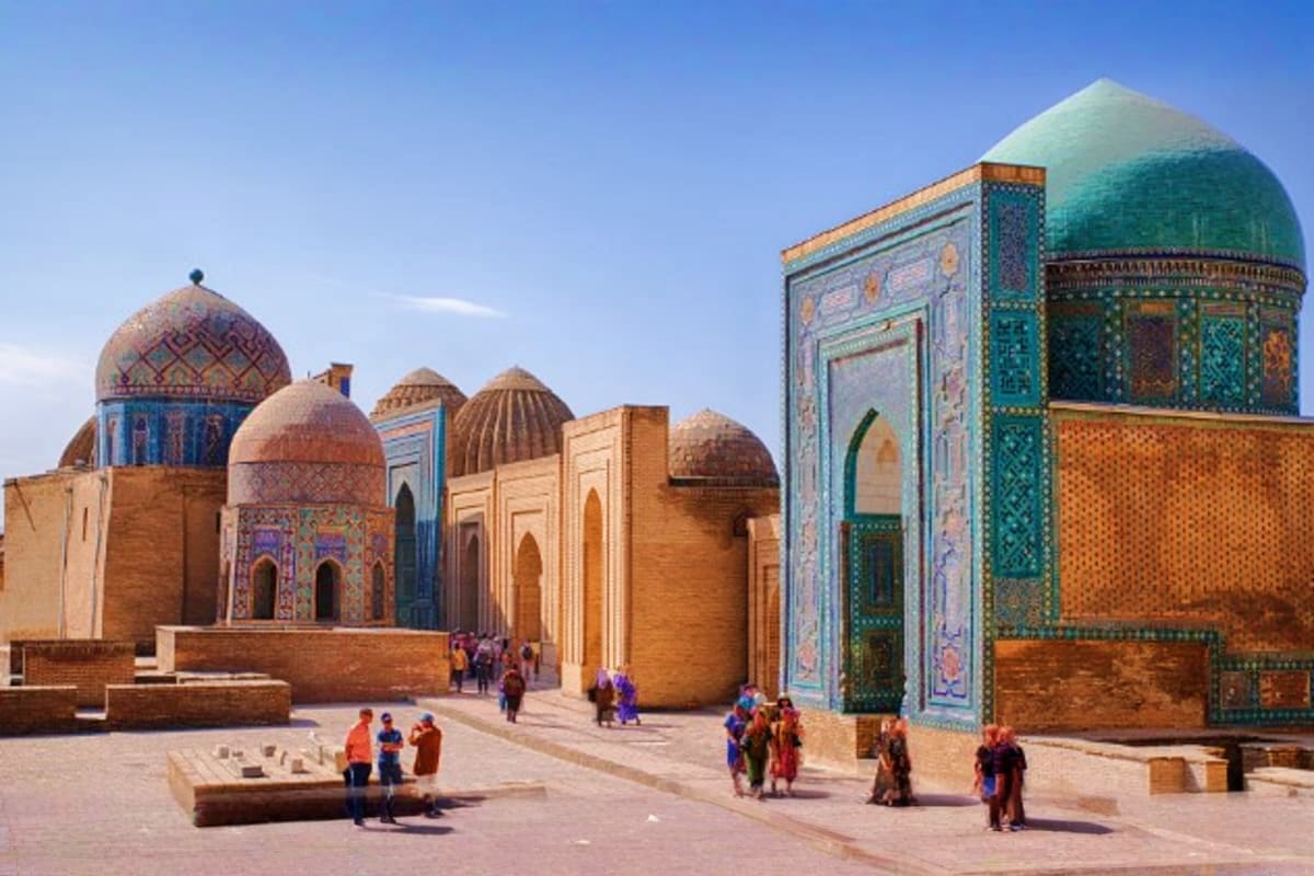 Historic Islamic architecture in Samarkand, Uzbekistan featuring ornate turquoise domes and intricate tilework with visitors 