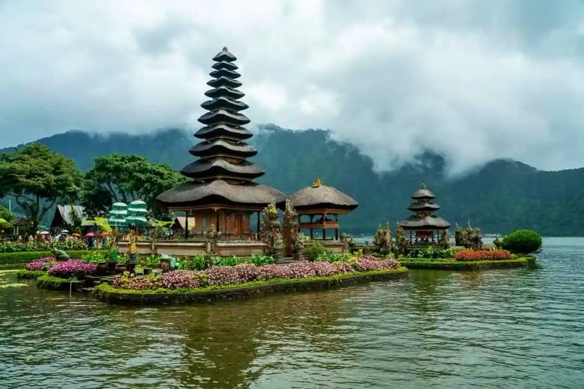 Pura Ulun Danu Bratan temple with tiered pagoda roof on lake surrounded by purple flowers and mountains in Bali, Indonesia