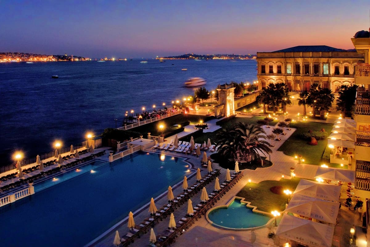 Charismatic Turkey Luxury waterfront resort at twilight with illuminated pool, umbrella loungers, and Bosphorus strait view with boats and Istan