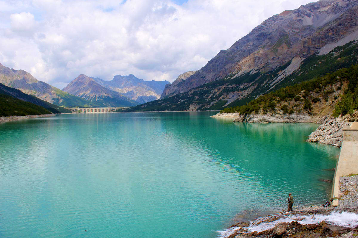 Turquoise alpine lake surrounded by snow-capped mountains and rocky shores in Uzbekistan's Tian Shan region
